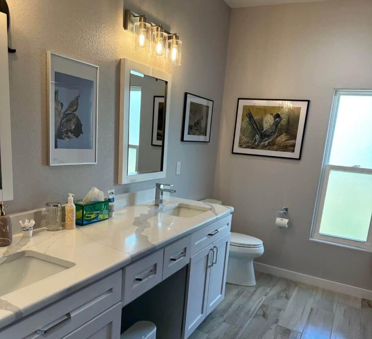 Bathroom with a double vanity and framed prints after a house cleaning