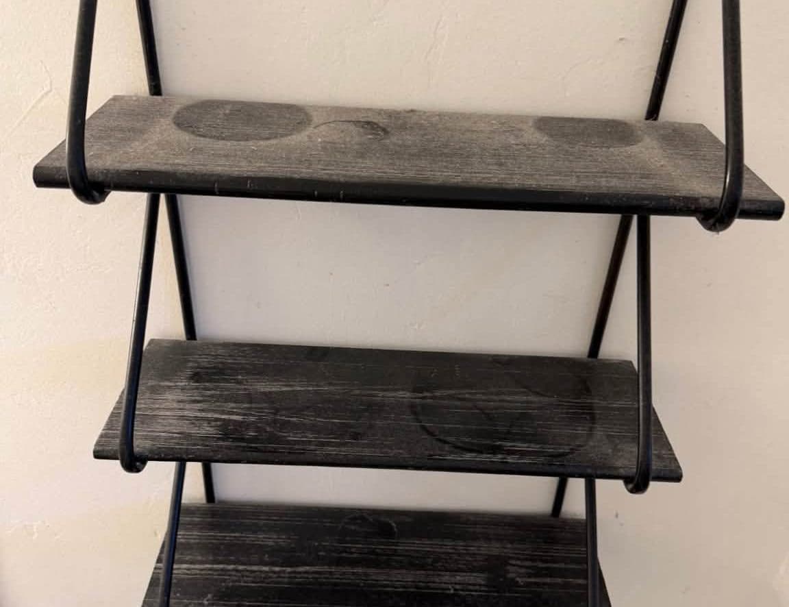 Black bathroom shelf covered in dust before a deep cleaning