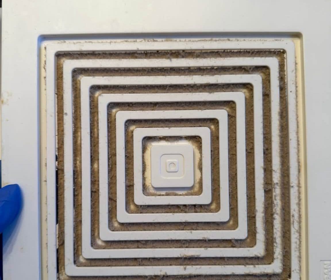 Bathroom exhaust vent cover thick with dust before a deep cleaning