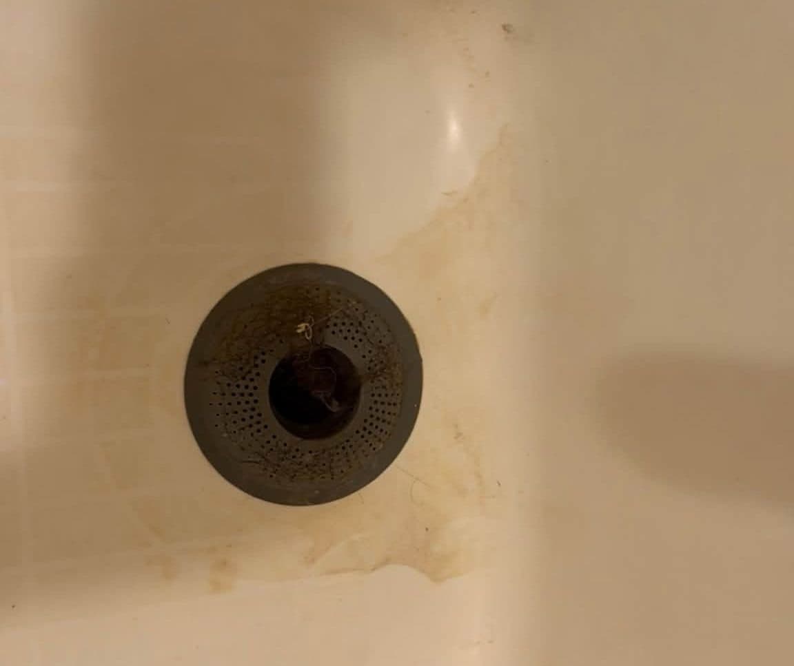 Bathtub drain with rust staining before a deep cleaning