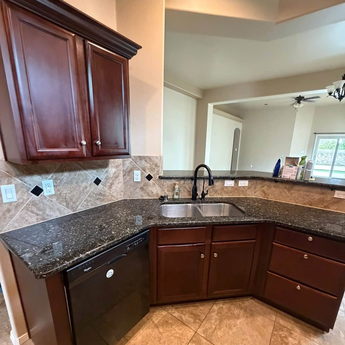 Empty kitchen with granite counters and cherry cabinets after a move-out cleaning in the Las Cruces area
