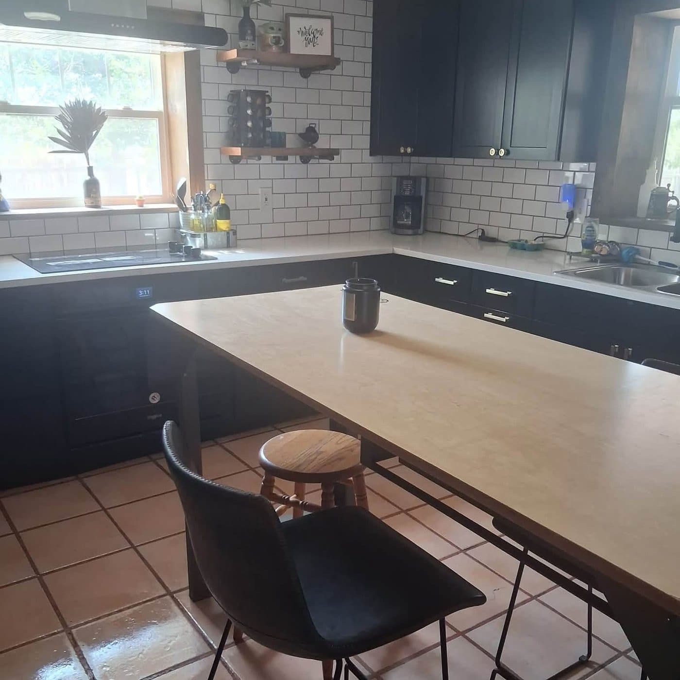 Kitchen with navy cabinets, subway tile and a clean island after a house cleaning