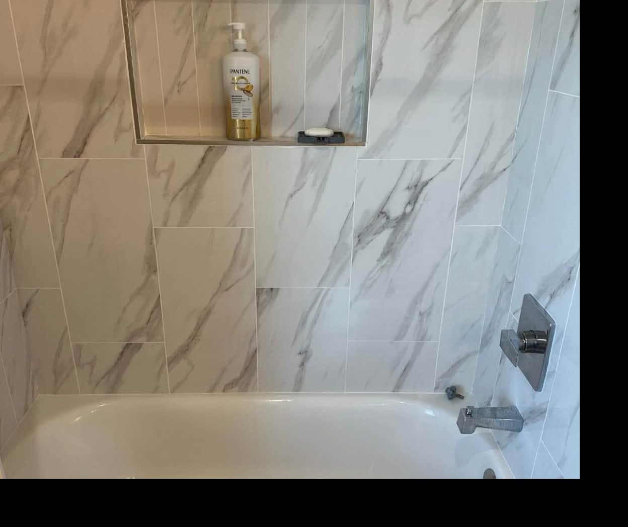 Marble tile tub and shower with a clean niche after a deep cleaning