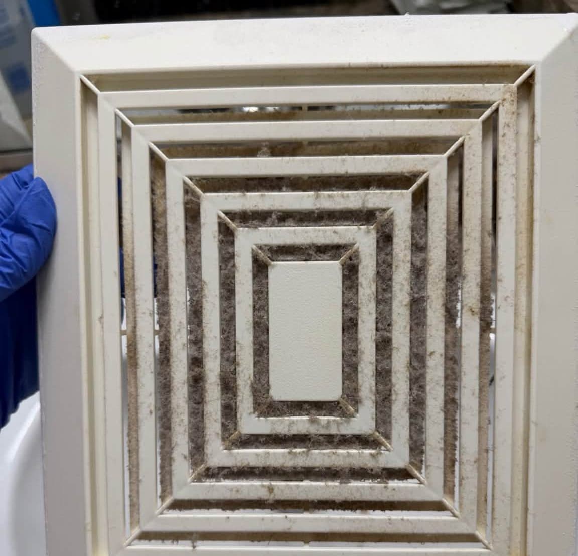 Rectangular ceiling vent cover coated in dust before a deep cleaning
