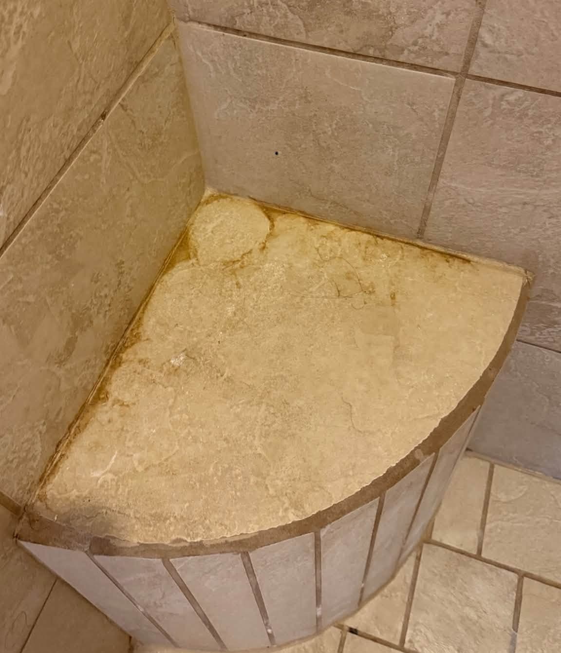 Before photo from Kat's Cleaning Services, a house cleaning company in Las Cruces: a tiled shower bench with orange hard water staining