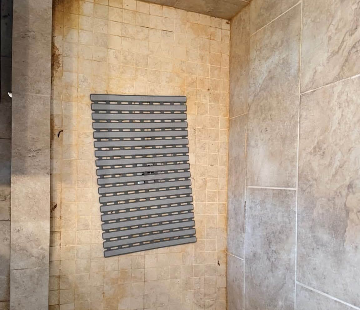 Mosaic tile shower floor with a stained bath mat before a deep cleaning
