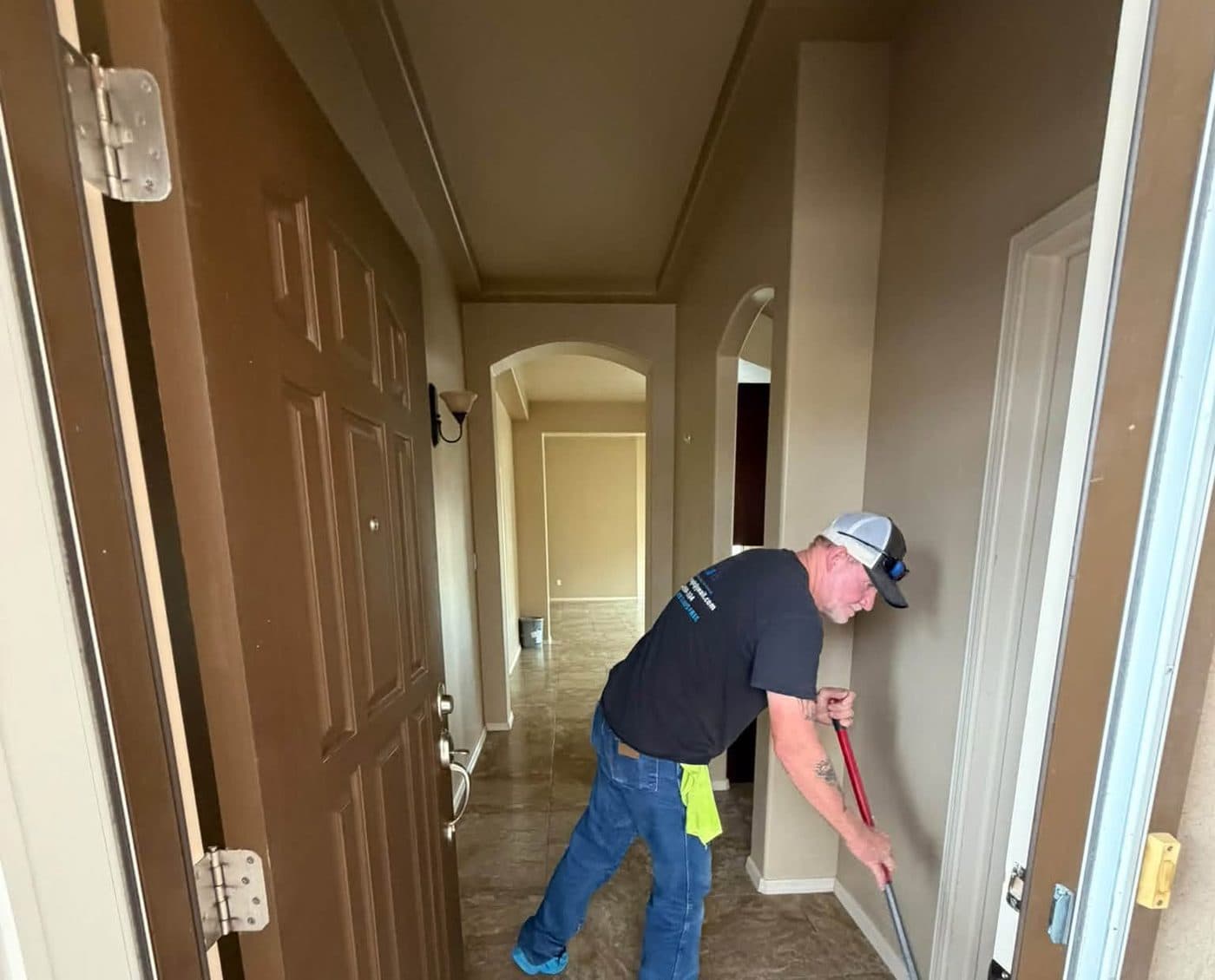 A Kat's Cleaning Services team member in shoe covers and gloves cleaning a hallway floor